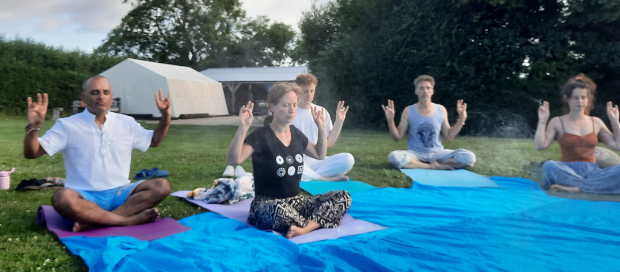 Group meditating outdoors at sunrise